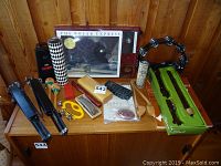 Overview of musical instruments spread on wooden surface including books, maracas, cowbell, tambourine, harmonicas, music stands.