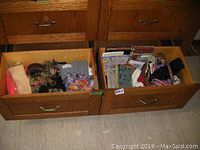 Two open bottom drawers showing assorted women's clothing and accessory items including sweaters, scarves, stationary, and other items.