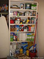 Full view of shelving unit with various cleaning supplies, paper towels, toilet paper, mop with bucket, and ironing board.