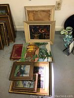 Collection of framed original oil paintings stacked and leaning, showing size and frame style variations