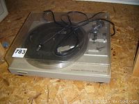 Front view of Pioneer PL-514 record player with transparent plastic dust cover and power cord placed on turntable.