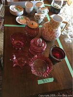 Various cranberry glass and ceramic serveware arranged on table, showing rough number tag 827