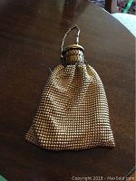 Front view of gold mesh evening bag with chain handle and bottle-cap style closure