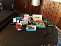 Overview of a table displaying multiple jewelry items including bracelets, pins, earrings in boxes and small bags