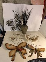 Overall view of five pieces of metal wall art and ceramic vase with twigs on white background