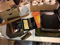 Overview of multiple office supplies including lamp, rulers, scissors, envelopes, file organizers, and boxes.