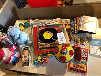 Top view of assorted children's vintage toys, records, and small items on a table including a blue stuffed dog, toys, and records.