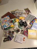 Overview of all crafting supplies showing stickers, inks, sponges, adhesives, papers, and embellishments spread on table.