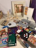Photo showing overall layout of craft items including easels, framed art, notebooks, and colored pencils
