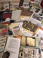 Wide layout of multiple scrapbooking kits and materials including paper packs, embellishments, and album kits arranged on table