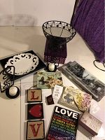 Top-down view of lot items arranged on a surface including candle holders, decorative plates, signs, and wire basket stand.