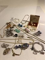 Overview of vintage jewelry lot showing multiple floral-themed earrings, faux pearl bracelets, silver and gold tone necklaces and brooches.
