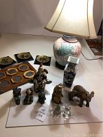 View of entire lot showing lamp, vases, multiple figurines, and decorative plates on table