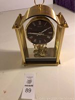 Front view of Seiko brass-tone mantel clock with black Roman numeral dial and glass sides.