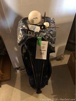 Photo of navy blue Mike Weir golf bag with various golf accessories on top and a maxsold tag.