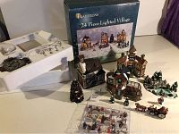 Full view of set including box showing 24 pieces: buildings, figurines, Christmas tree, horse-drawn carriage.