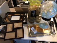 Overview of assorted frames, glass globe, mirrored tray, and small decorative items