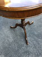 Side view showing wooden pedestal legs and table surface edge.