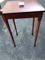 Small wooden side table with four tapered legs and dark brown finish.