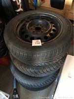 Stacked tires with steel rims showing tread and rust on rims