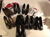 Top-down view showing all 10 pairs of shoes on a white surface including slippers, heels, loafers, and boots.