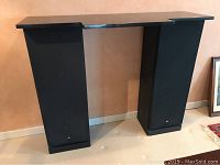 Front view showing pair of tall black Mitsubishi floor speakers with custom granite top spanning both speakers.