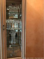 Full view of the crystal stemware, vase, and cake plate displayed inside cabinet shelving