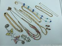 Photo showing the full assortment of 10 necklaces, 1 bracelet, and 1 pair of vintage clip earrings laid out on a white background.
