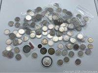 Overview photo showing the assortment of US coins including quarters, half dollars, and other coins with some in plastic bags and holders.