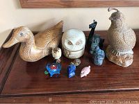 All items grouped on wooden surface showing duck, quail, owl, and smaller figurines