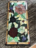 Full view of a stained glass look panel with a floral design in multiple colors including browns, black, purples, greens, amber, and yellow.