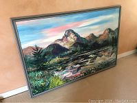 Full view of the large framed oil painting showing the mountain scene and body of water.