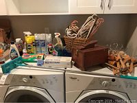 Wide view showing cleaning supplies, wooden hangers in basket, and wooden box on top of washing machine