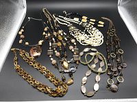 Overview of all seven necklaces laid out on a black background, showing various styles including chunky chains, multi-strand beads, and mixed materials.