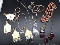 Overview of entire lot showing various jewelry pieces laid out on black background.