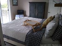 Full view of made king bed with white comforter, decorative pillows, and black metal frame visible