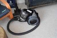 Samsung canister vacuum cleaner with power hose and base unit on carpeted floor.