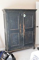 Front view of closed armoire showing two-panel doors and distressed paint finish