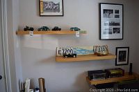 Wide shot of wall shelves displaying six model cars and two Ontario license plates; one plate included, one plate excluded.