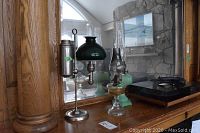 Three oil lamps on wooden sideboard with mirrored backing