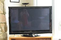 Full front view of 50" Hitachi TV on wooden stand showing overall condition and screen.