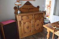 Front view of antique oak server buffet showing two drawers and two cabinet doors, carved accents and removable backsplash.