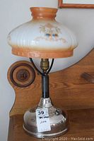 Full image of the antique converted gas lamp showing the base and porcelain shade with floral pattern.