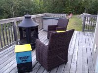 Outdoor deck scene with black metal fireplace and two dark brown wicker chairs