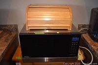 Microwave with wooden bread box on top, showing overall appearance and size relation