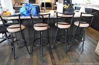 Set of four kitchen bar stools arranged in a row showing their backs and seats made of ultra suede.
