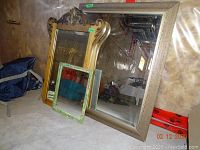 Full shot of three mirrors: the small painted wood mirror, the antique carved wood mirror, and a large mirror in the background not included in lot.