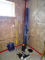 Photo of corner with hockey sticks, skates, yoga roller, hockey pucks, softballs, child's bat, and backpack