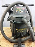 Front view of Craftsman wet/dry shop vacuum with hose coiled around and attachments visible.
