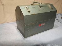Closed gray metal Sears Craftsman toolbox on a gray fabric surface showing the overall size and condition.